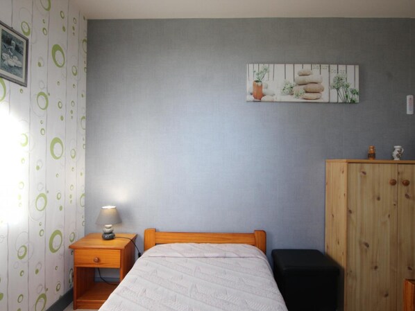 A bedroom with a bed, a nightstand with a lamp, a wooden wardrobe, and a wall with a painting. - Charming renovated farmhouse with garden (Folligny)