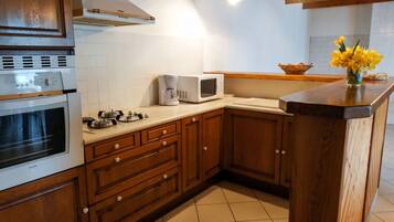Een keuken met houten kastjes, een ingebouwde oven, een magnetron en een koffiezetapparaat op het aanrecht.