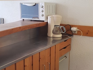 Eine Küchenzeile mit Toaster, Kaffeemaschine und Mikrowelle auf einer Holzausziehtafel.