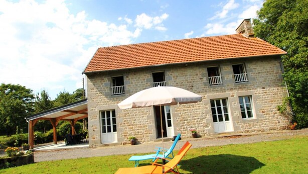 A stone house with a tiled roof, a covered patio, and two lounge chairs. - Countryside house in Saussey, 4 bedrooms, peace and comfort (Beslon)