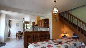 A spacious living area with a large bed, a dining table, and a kitchen in the background. - Countryside house in Saussey, 4 bedrooms, peace and comfort (Beslon)