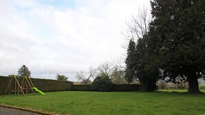 A grassy yard with a swing set and a large tree. - Countryside house in Saussey, 4 bedrooms, peace and comfort (Beslon)