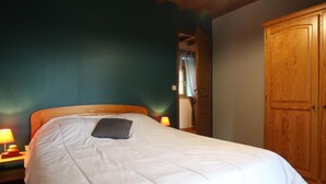 A bedroom with a wooden bed, a nightstand with a lamp, and a wardrobe. - Countryside house in Saussey, 4 bedrooms, peace and comfort (Beslon)