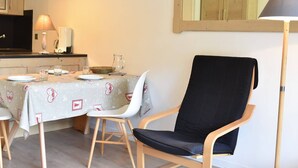 Un comedor con una mesa preparada para dos, una silla negra, una lámpara y un espejo en la pared.