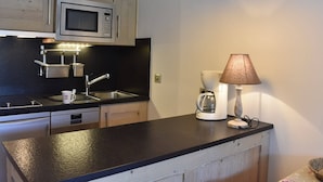 Cocina pequeña con microondas, fregadero y cafetera.