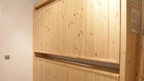 Un armario de madera con dos repisas, una puerta y un letrero colgado en la pared.