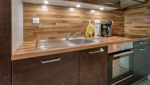 Une cuisine moderne dotée de meubles en bois, d’appareils électroménagers en acier inoxydable et d’un four encastré.