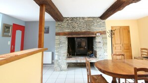 A room with a stone fireplace, wooden beams, a dining table, and chairs. - Cozy Stone Farmhouse with Garden, Near Saint-Lô – Sleeps 4, Modern Amenities, Pet-Friendly (Baudre)