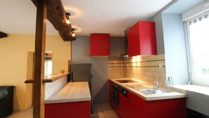 A kitchen with red cabinets, a stainless steel refrigerator, and a window providing natural light. - Cozy Stone Farmhouse with Garden, Near Saint-Lô – Sleeps 4, Modern Amenities, Pet-Friendly (Baudre)