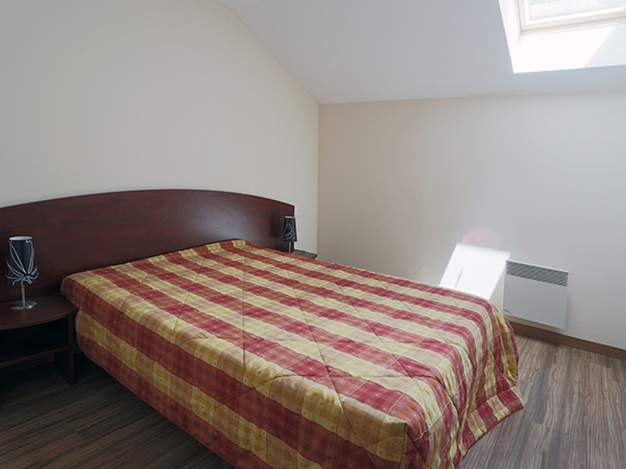 Un dormitorio con una cama, dos mesitas de noche y un ventanal.