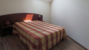 A bedroom with a bed, a nightstand, a lamp, and a skylight.
