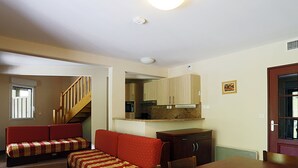 A compact living space with a dining area, a kitchenette, and a staircase leading to another level.