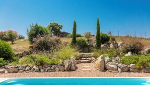 A pool with a stone pathway leading to a house surrounded by greenery and trees. - Beautiful villa ' Les Figuiers' with pool between sea and mountain (Figari)
