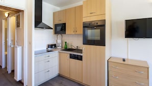Una cucina moderna con mobili in legno, un forno a microonde, un forno, una lavastoviglie e una televisione a schermo piatto.