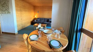 A wooden interior with a round dining table set for four, a sofa, and a lamp. - 2-room apt for 4, 150m from slopes, Méribel (Méribel)