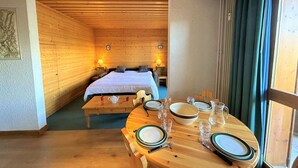 A wooden room with a bed, a dining table set for two, and a view of another room with a bed. - 2-room apt for 4, 150m from slopes, Méribel (Méribel)