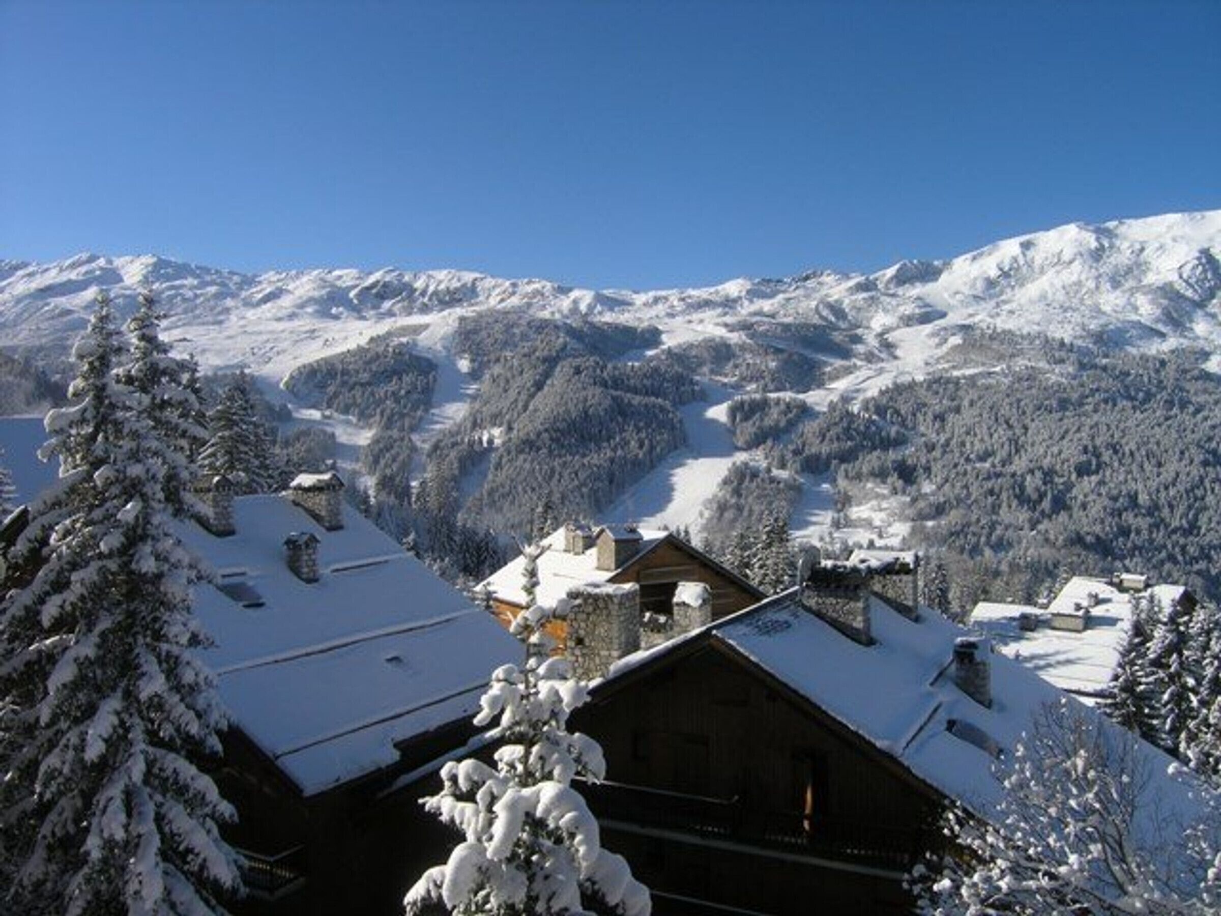 A mountain lodge with a wooden exterior, surrounded by snow-covered trees and mountains.