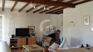 Una sala de estar con televisor, muebles de madera, chimenea y techo con vigas a la vista.