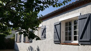 Un edificio con fachada de estuco, molduras blancas y contraventanas oscuras.