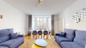 Ein modernes Wohnzimmer mit zwei Sofas, einem Couchtisch und einem Essbereich mit Tisch und Stühlen.