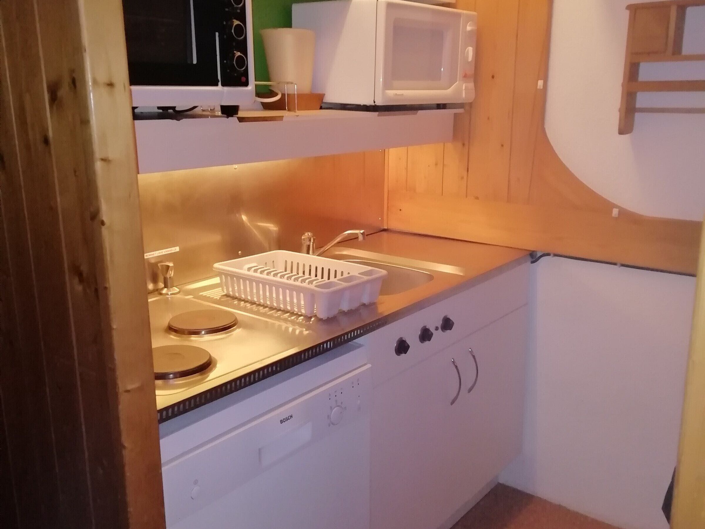 Cocina compacta equipada con microondas, lavabo y lavavajillas Bosch.