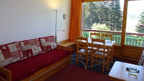 A cozy room with a wooden bench, a small table, and a red sofa.