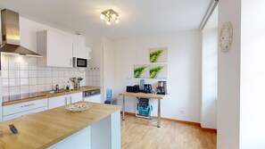 Una cucina moderna con mobili bianchi, un forno a microonde, una macchina da caffè e un piccolo tavolo con un cesto.