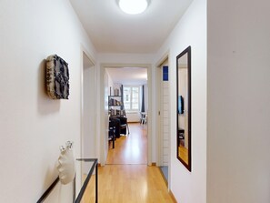A hallway with a bookshelf, a mirror, and a decorative wall piece. - hartmann 80m2 city center    2br (Colmar)