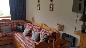 Una habitación acogedora con un sofá cama de madera, una mesita pequeña y un televisor.