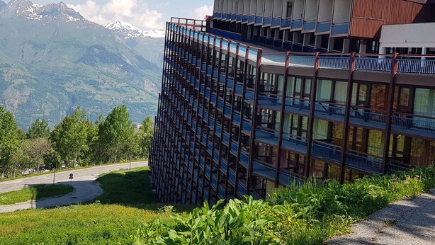 Un edificio moderno con varios balcones que dan a un paisaje montañoso.