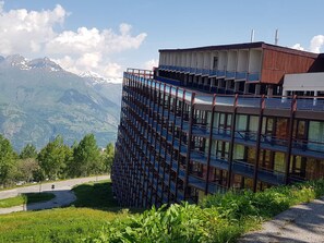 A modern building with multiple balconies overlooking a mountainous landscape.