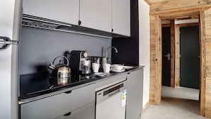 A modern kitchen with grey cabinets, a black countertop, a coffee machine, and a kettle.