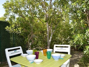 An outdoor dining area with a table set for four, surrounded by lush greenery and trees.