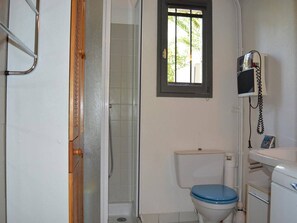 A bathroom with a shower, toilet, and a telephone.
