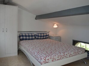 A bedroom with a bed, a nightstand, a lamp, and a wardrobe.