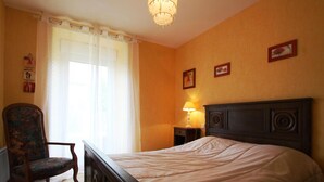 Un dormitorio con cama, una silla, una mesita de noche y una lámpara.