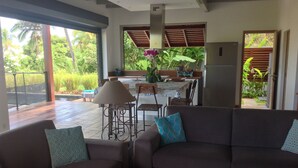 A modern living room with a sofa, a coffee table, and a dining area with chairs and a table.