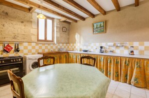 A kitchen with a dining table, wooden beams, a washing machine, and a window. - Homerez - Spacious House - Marcellus - 400 m² - Garden (Marcellus)