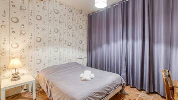 A hotel room with a bed, a nightstand, a lamp, and a curtain.