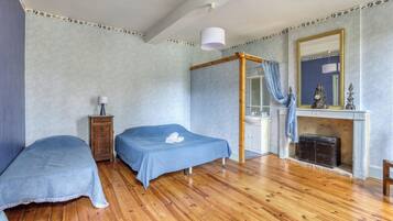 Un dormitorio con dos camas individuales, un aparador de madera, una mesita de noche, un espejo, una chimenea y un ventilador de techo.