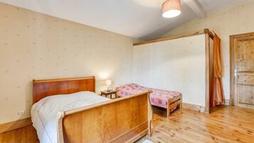 A bedroom with a wooden bed, a bedside table with a lamp, and a small chair.