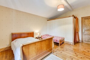 A bedroom with a wooden bed, a bedside table with a lamp, and a small chair. - Homerez - Spacious House - Marcellus - 400 m² - Garden (Marcellus)