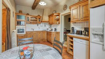 Una cucina con mobili in legno, un frigorifero bianco e un tavolo da pranzo con una tovaglia fantasia.