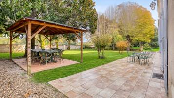 Un espace patio agrémenté d’une pergola, de meubles de jardin et d’une pelouse bien entretenue.