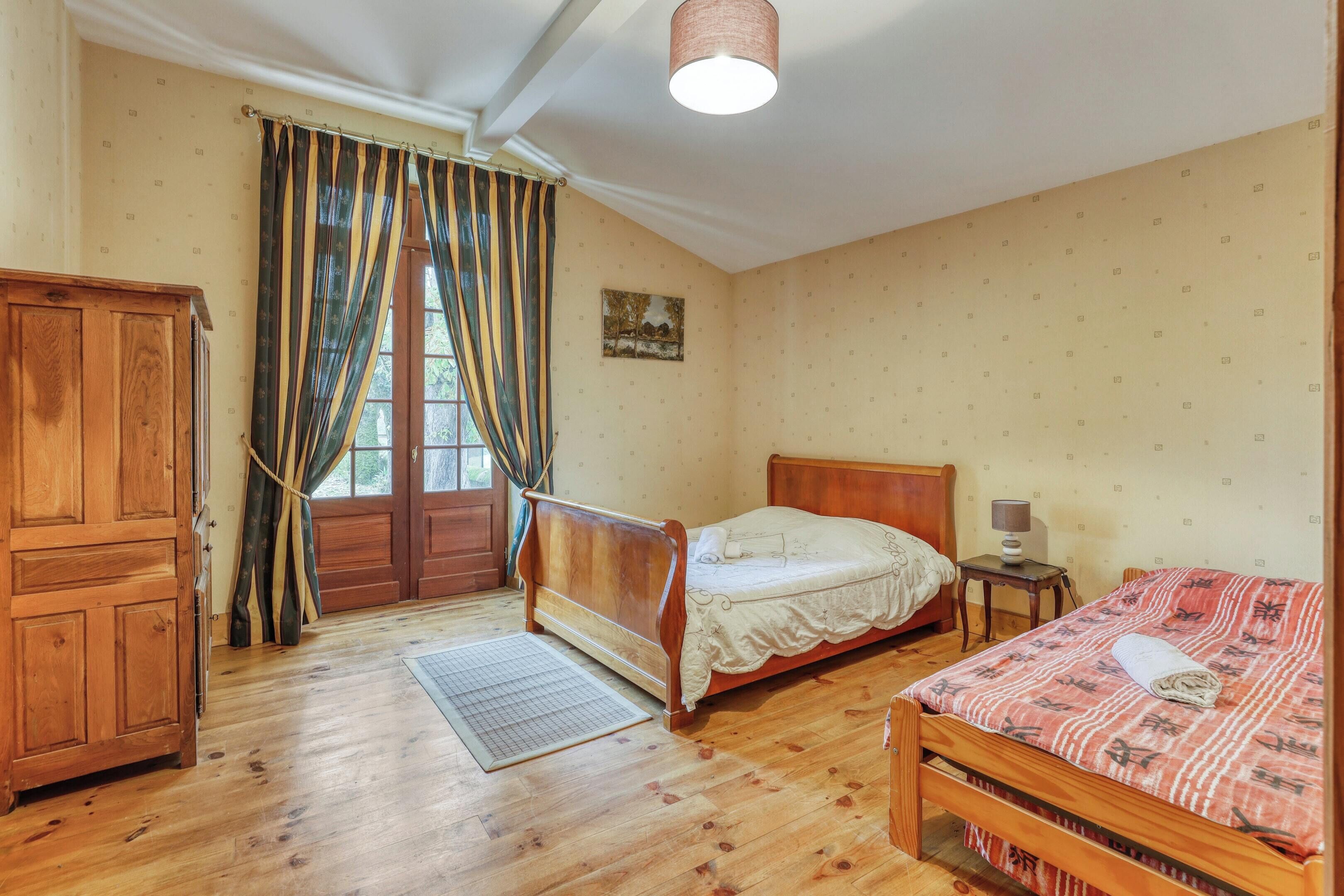 Quarto com cama de madeira, guarda-roupa de madeira e uma pequena mesa de cabeceira com abajur.