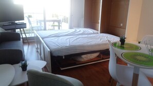 Une chambre d’hôtel de taille réduite, comprenant un lit, un petit bureau, une chaise et une table dont le plateau est vert.