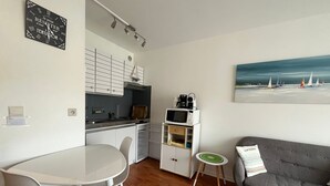 Un espace de vie compact comprenant un coin cuisine, un coin repas, un canapé et une petite table d’appoint.