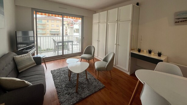 Un salon moderne comprenant un canapé, un téléviseur, une table à manger et un coin cuisine avec des placards.