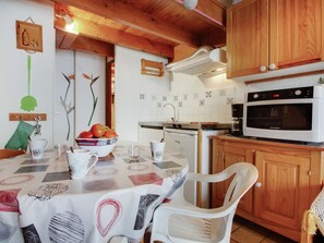 A kitchen with wooden cabinets, a microwave, a stove, and a dining table with chairs.