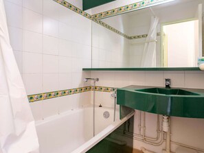 Een badkamer met witte betegelde muren, een groene wastafel en een douchegordijn.